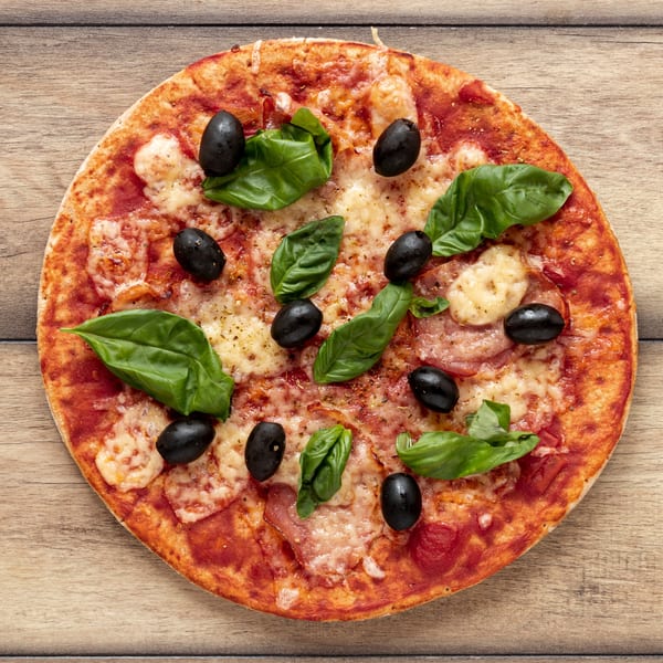 Runner Pizza Stoughton's pizza with black olives, basil, and cheese on a wooden table.