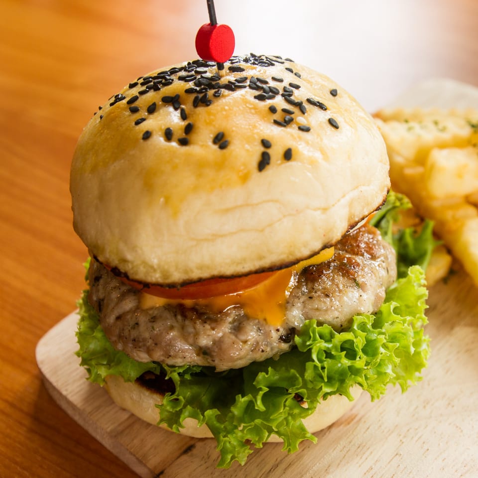 A Runner Pizza Stoughton burger with sesame seed bun, cheese, lettuce, and tomato, with fries.